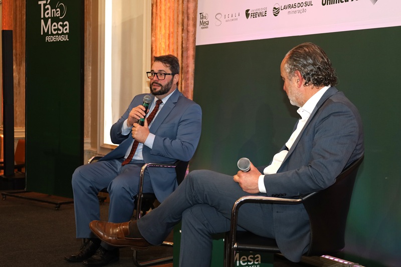 A foto mostra o presidente do TRT-RS, Alexandre, e Rodrigo Sousa Costa, presidente da Federasul, em debate, sentados em um palco.