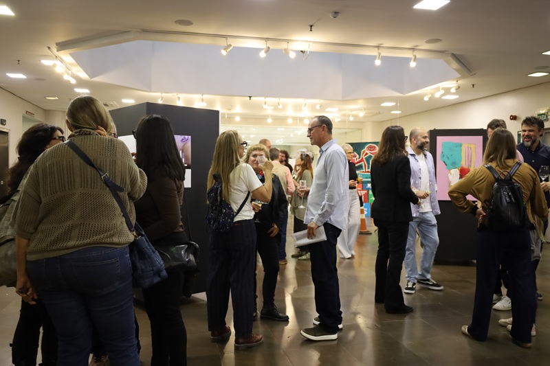 Imagem geral da abertura da exposição com vários grupos de pessoas conversando.