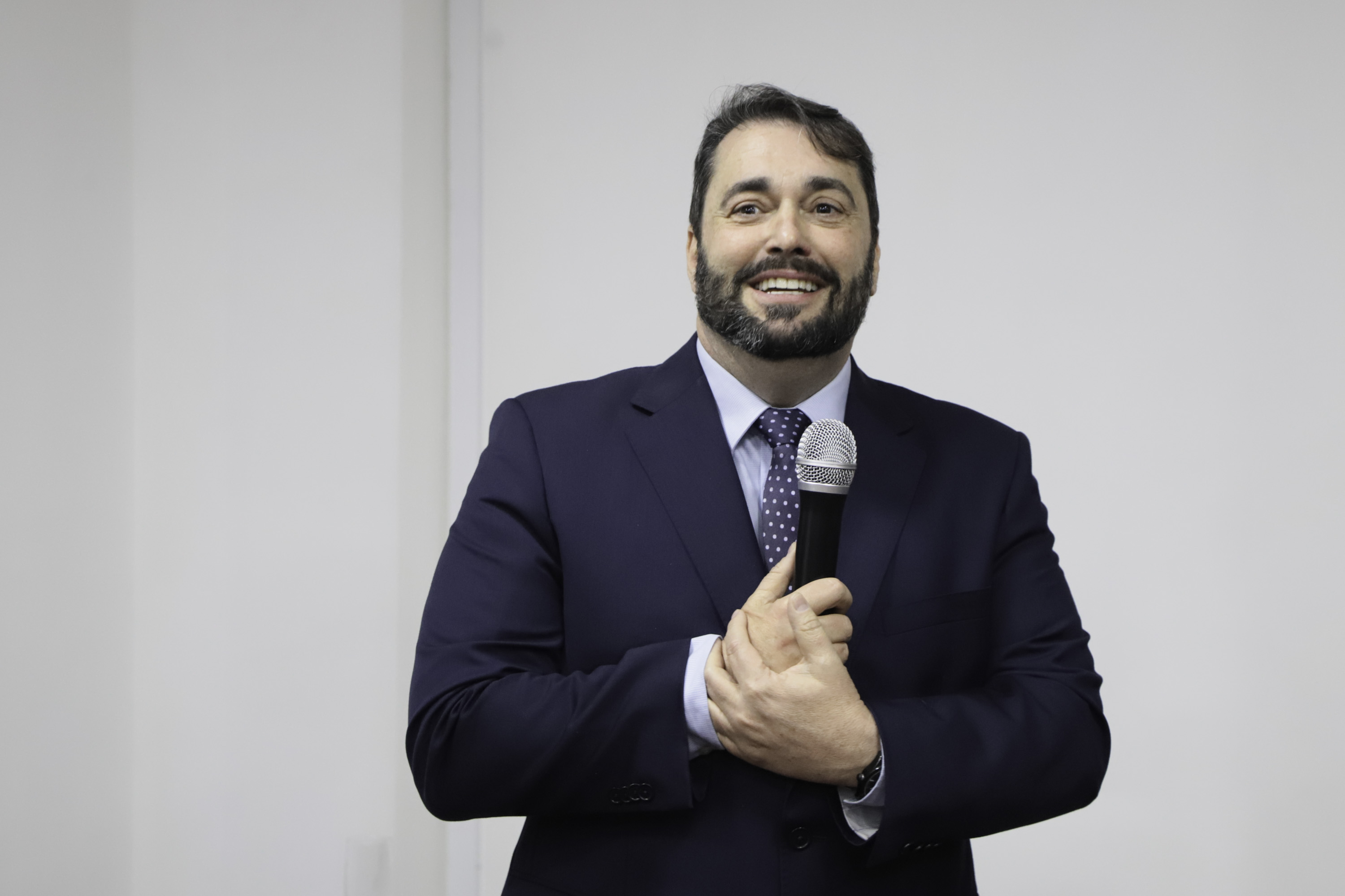 Alendre sorri e fala ao microfone de pé