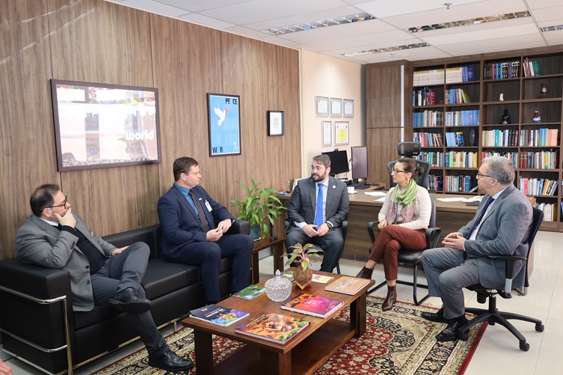 A foto mostra os presentes na reunião, sentados, conversando.