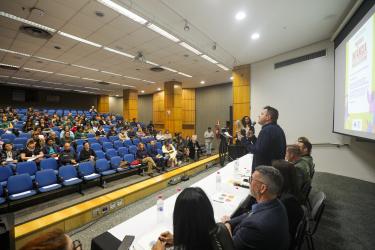 Público sentado assistindo uma pessoa discursando