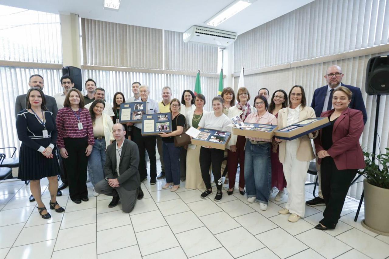 Participantes do evento posam para a foto mostrando os álbuns de fotos