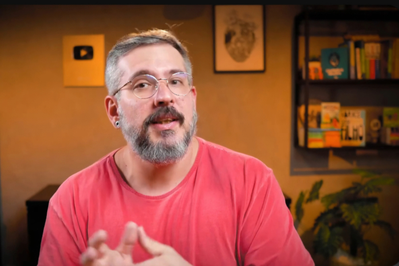 Print de tela mostra o palestrante Thiago. Ele é um homem de meia idade, com cabelos e barba grisalha. Tem a pele branca e usa uma camiseta vermelha.