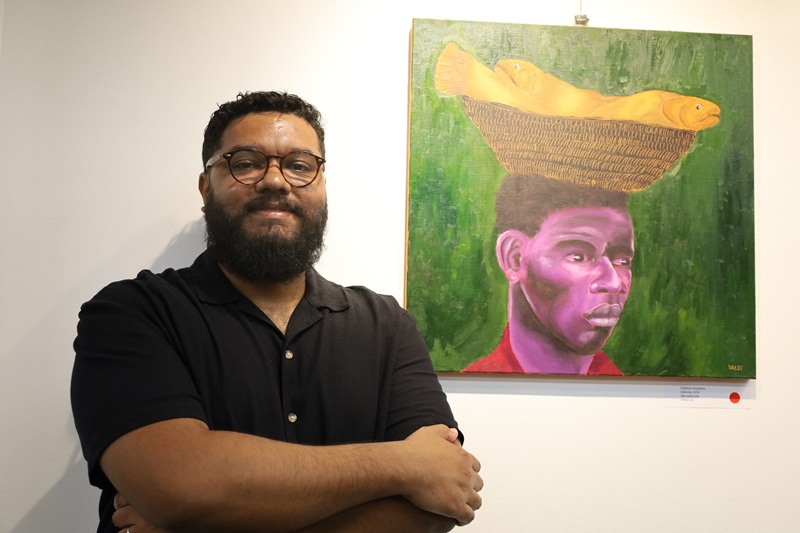 Imagem de Valdenar ao lado de um de seus quadros.