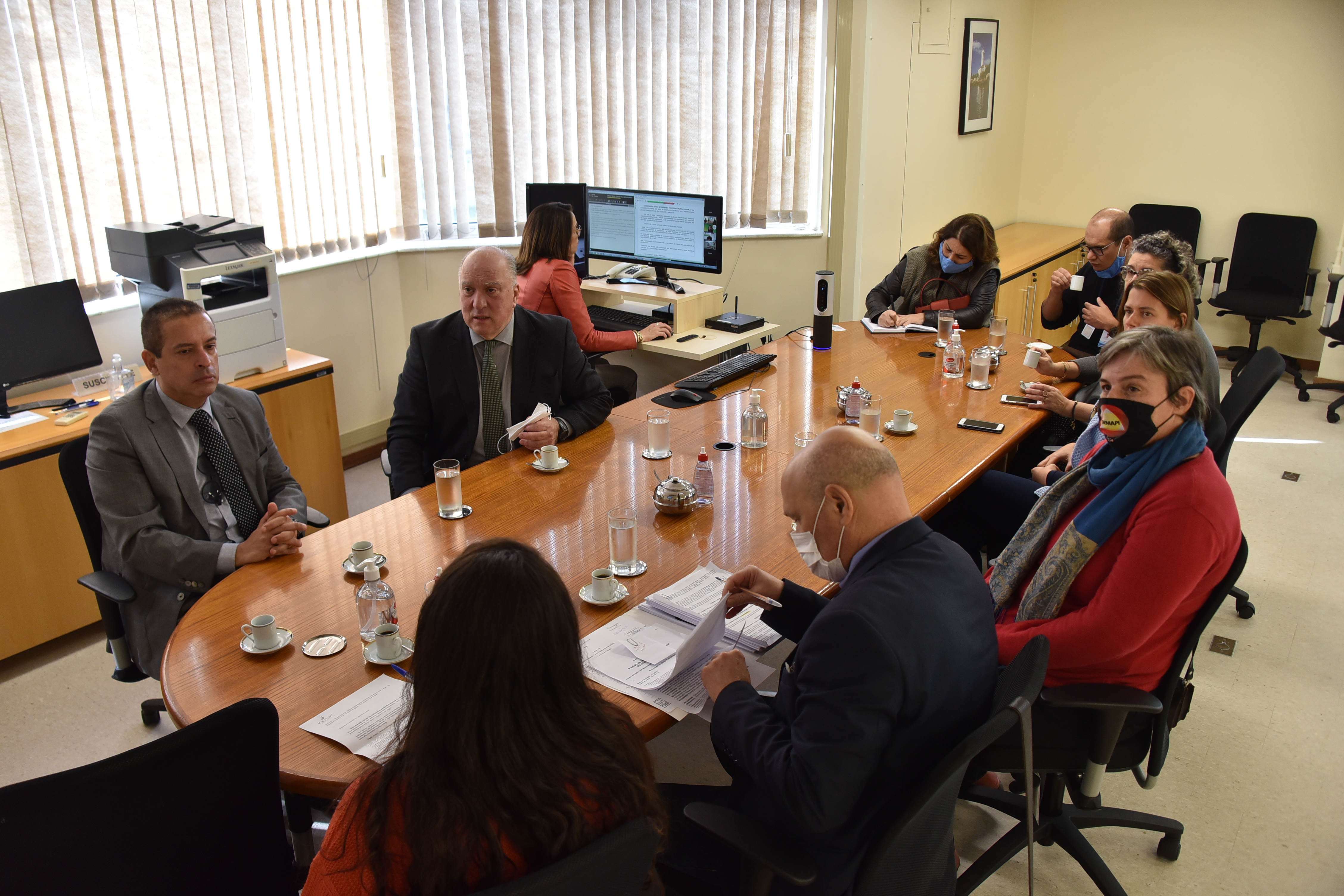 Foto dos participantes na mesa de negociação. Desembargador Ricardo aparece ao centro da imagem.