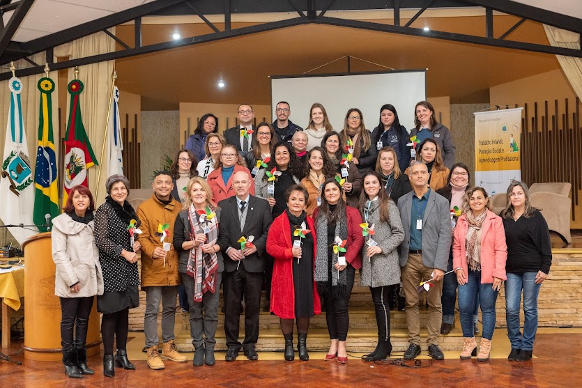 Foto posada dos participantes. Eles estão perfilados e seguram um catavento, símbolo da campanha contra o trabalho infantil.