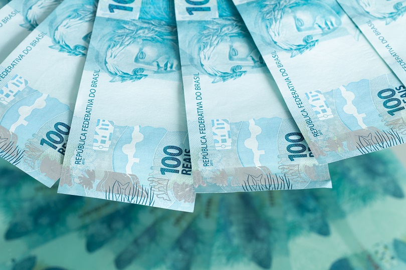 Foto ilustrativa de seis cédulas de cem reais dispostas em formato de leque.