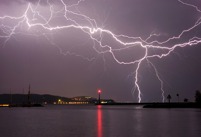 Foto ilustrativa em plano aberto de uma cidade sendo atingida por uma tempestade de raios elétricos.