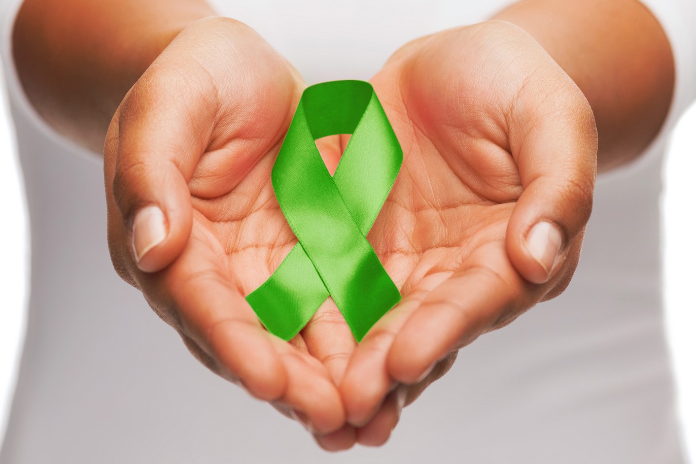 foto das mãos de uma pessoa em concha segurando uma fita verde