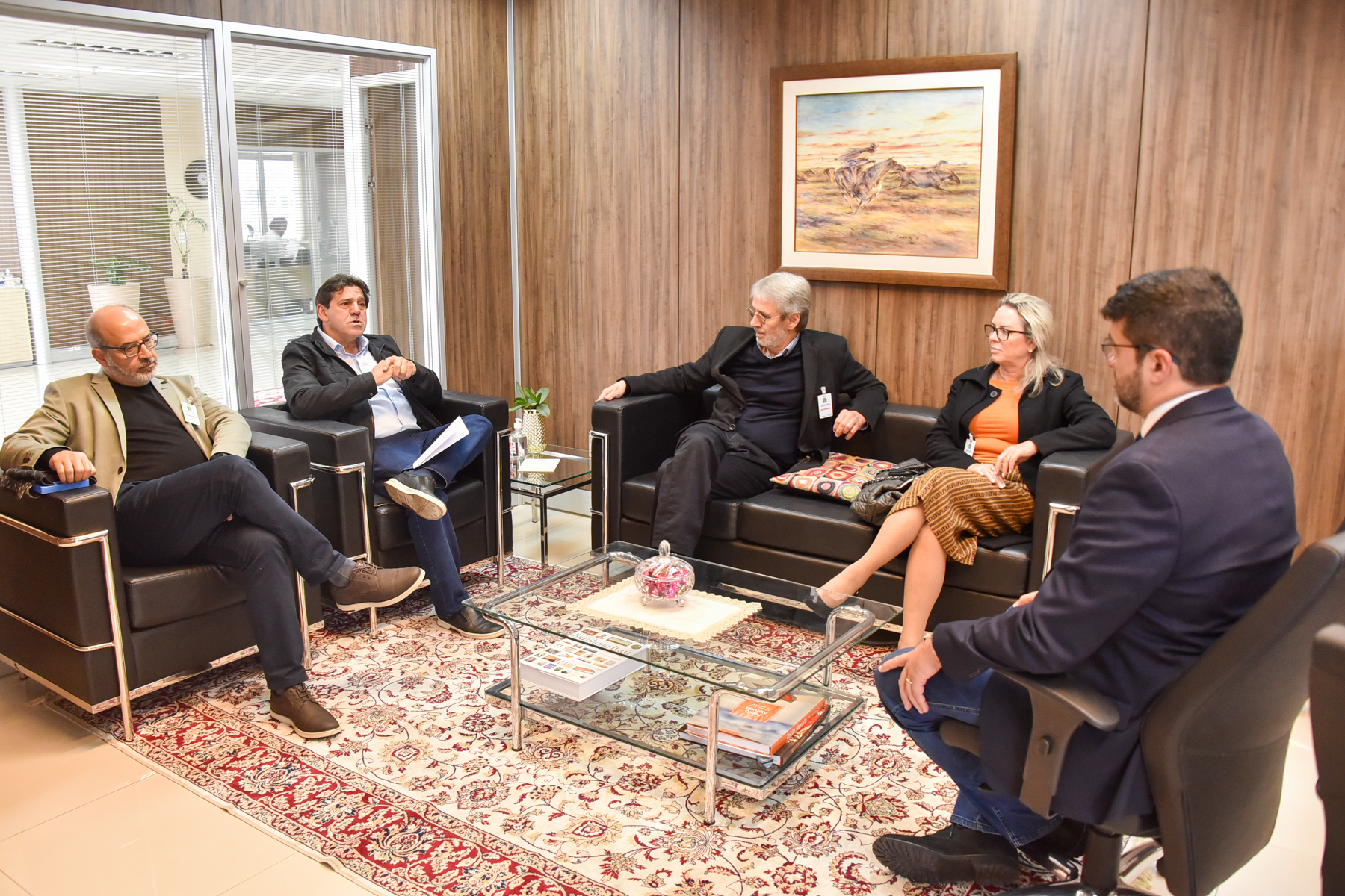 Foto da reunião, com os participantes sentados nas poltronas do gabinete