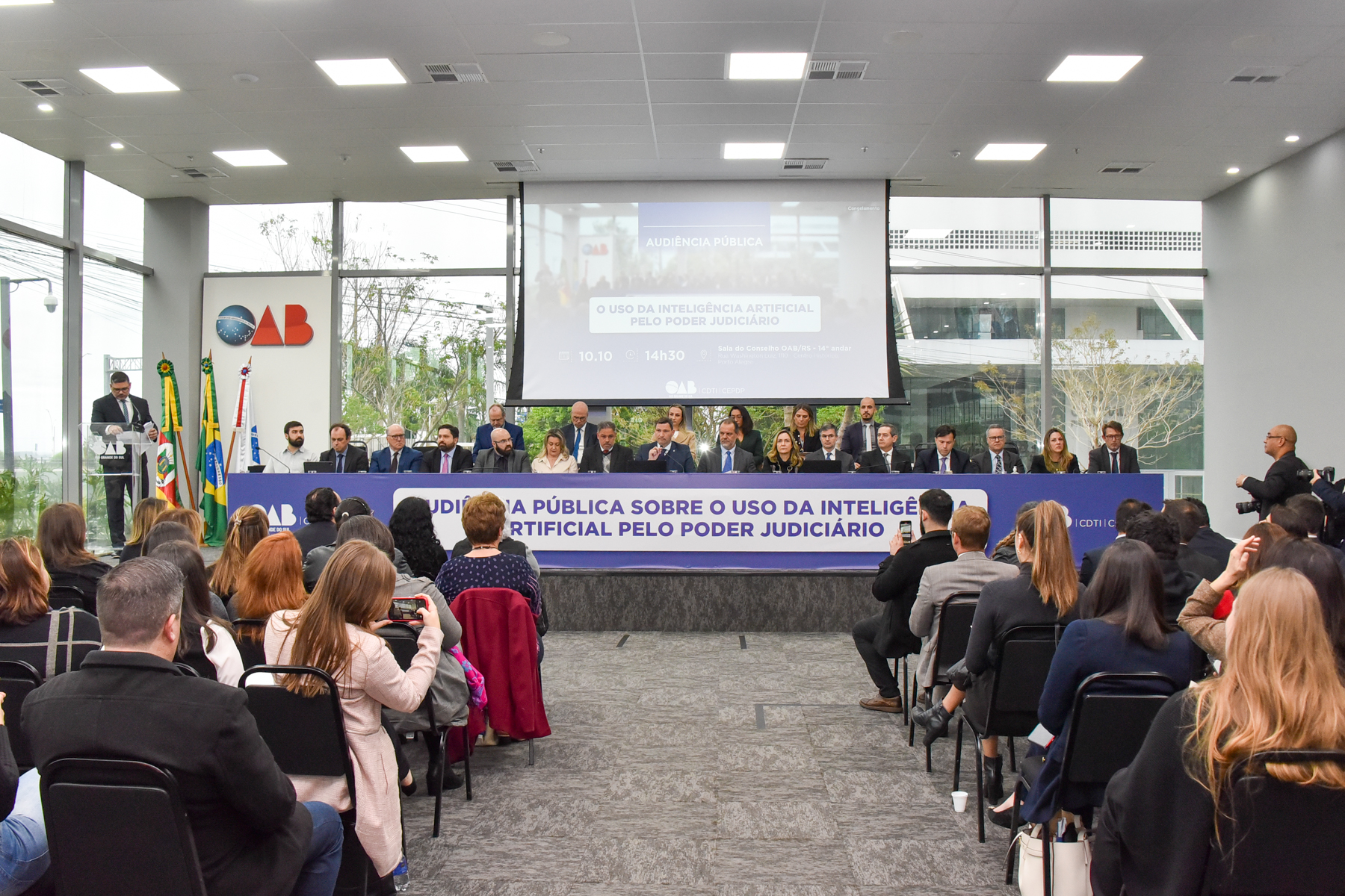 Foto da mesa oficial e parte do público da audiência
