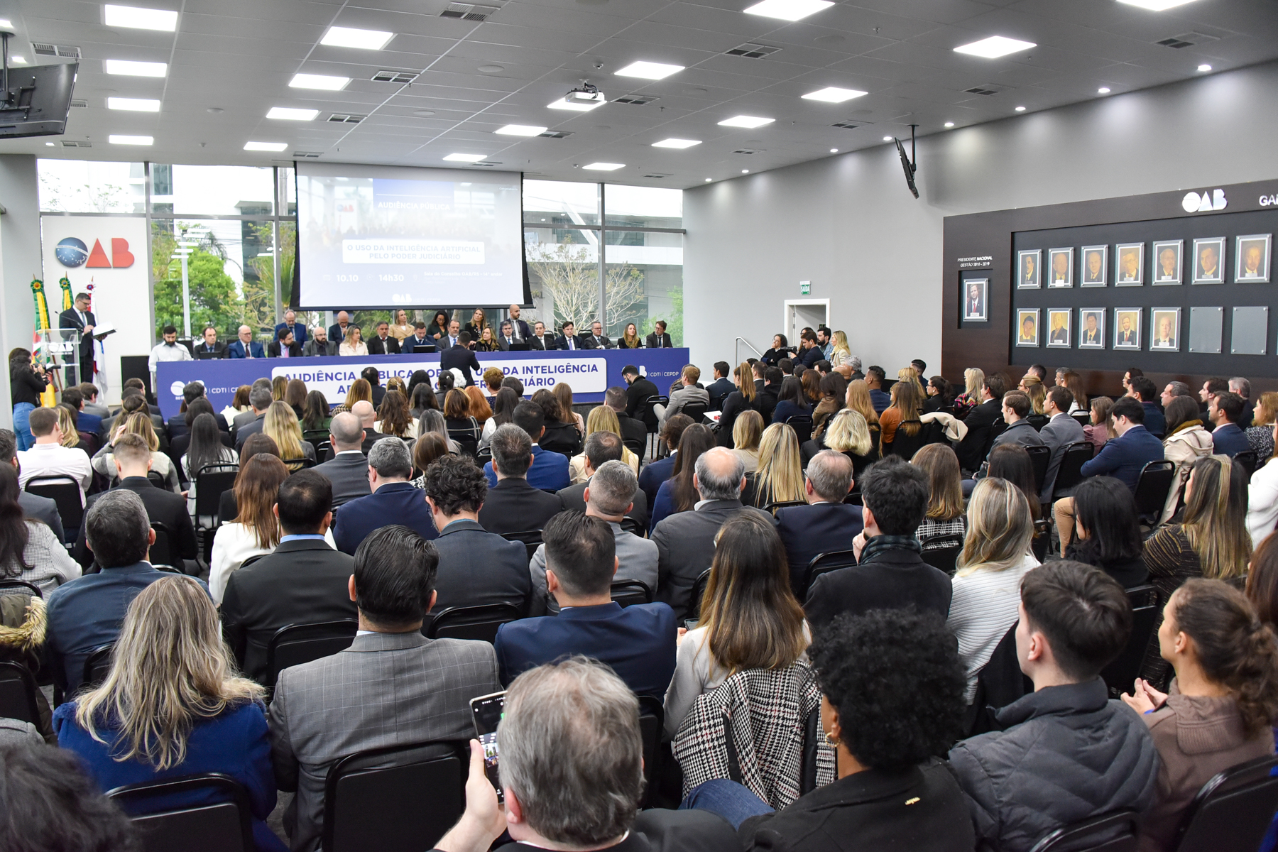 Público da audiência. Foto em ângulo aberto.