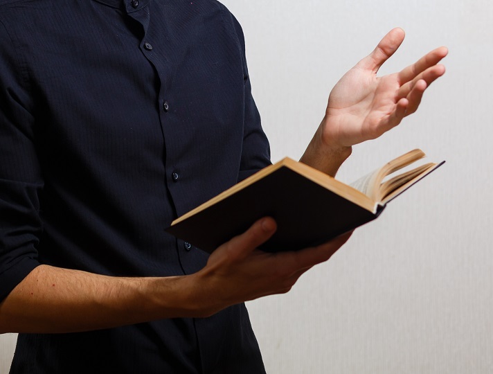 Homem de terno com livro aberto na mão.