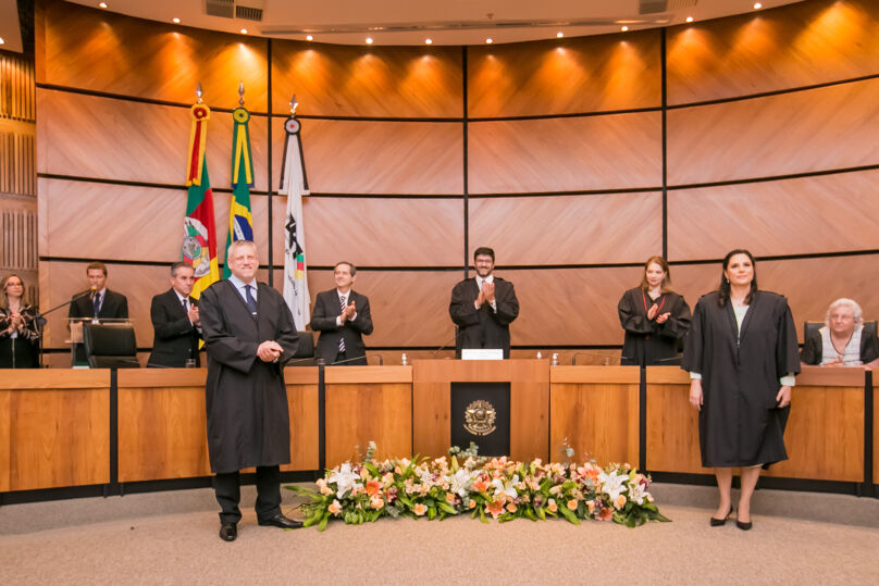 Foto dos empossados e da mesa da solenidade ao fundo