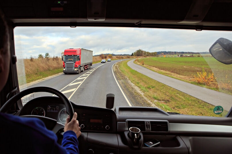 Foto ilustrativa de um homem que dirige um caminhão por estrada. 