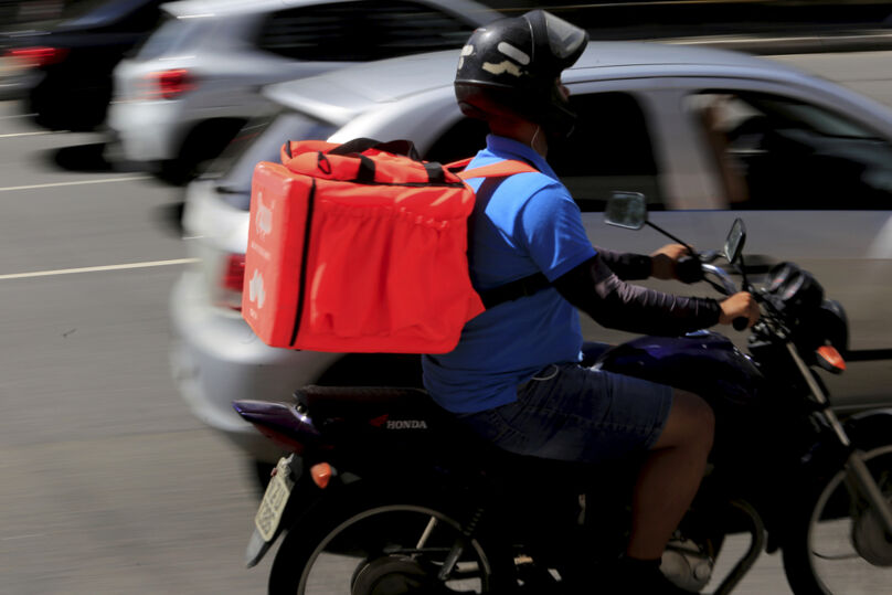 Entregador dirigindo motocicleta.