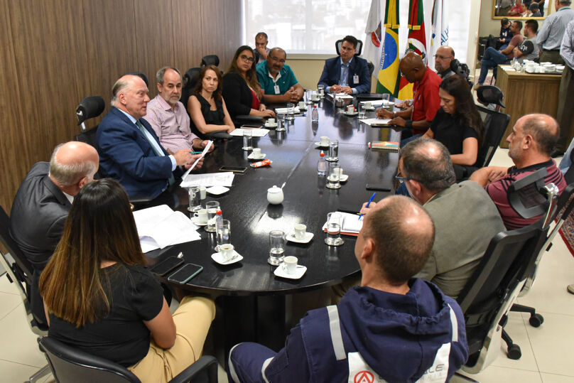 Fotos dos participantes sentados em torno da mesa da sessão de mediação no TRT-4