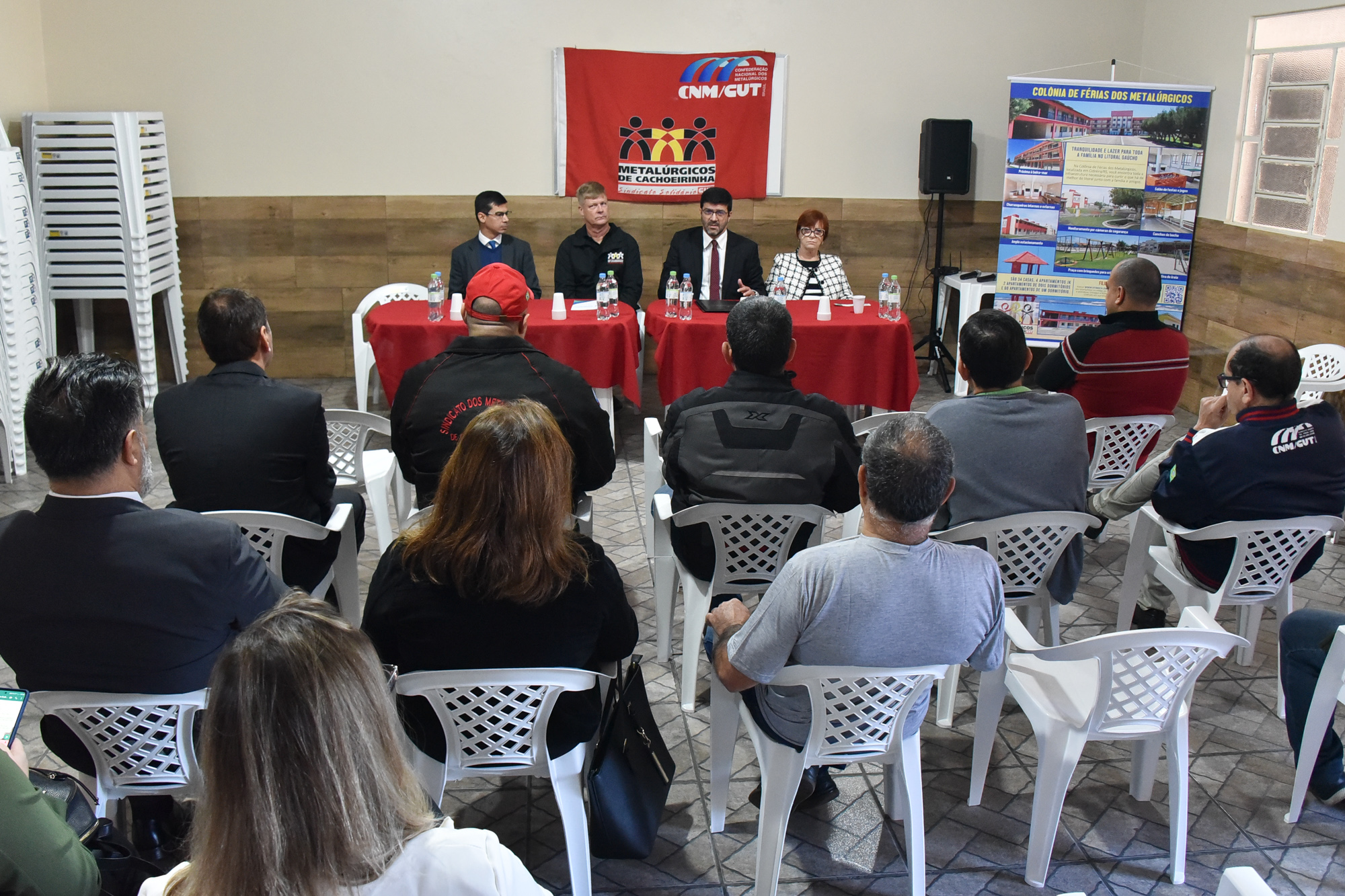 Presidente aparece ao fundo em uma mesa com o público de dirigentes sinidicais de cosas em primeiro plano