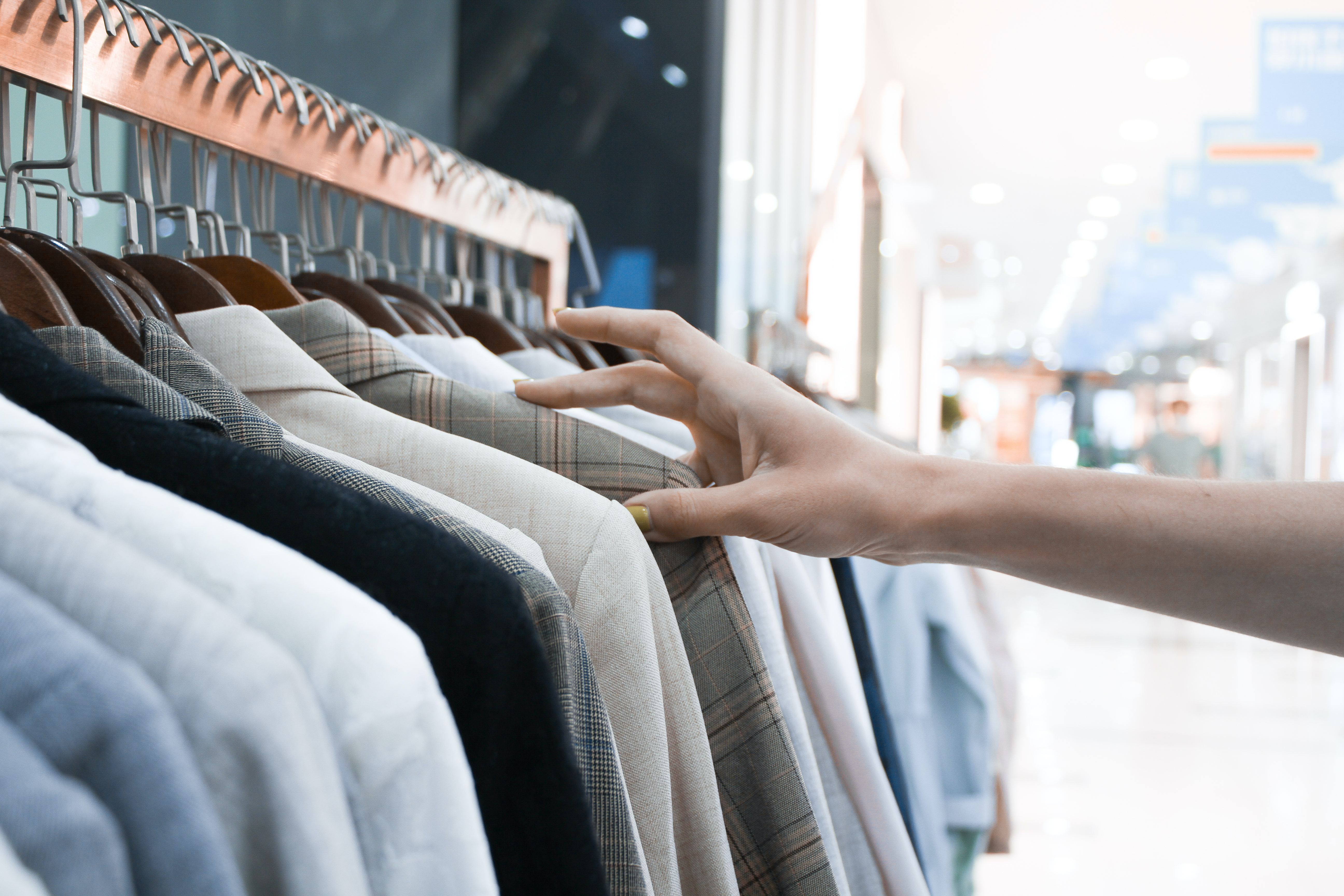 Imagem ilustrativa de uma pessoa escolhendo roupas numa loja