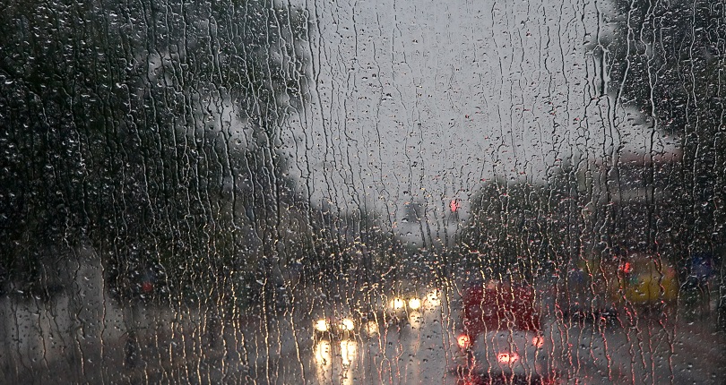 Foto de forte chuva escorrendo por um vidro.