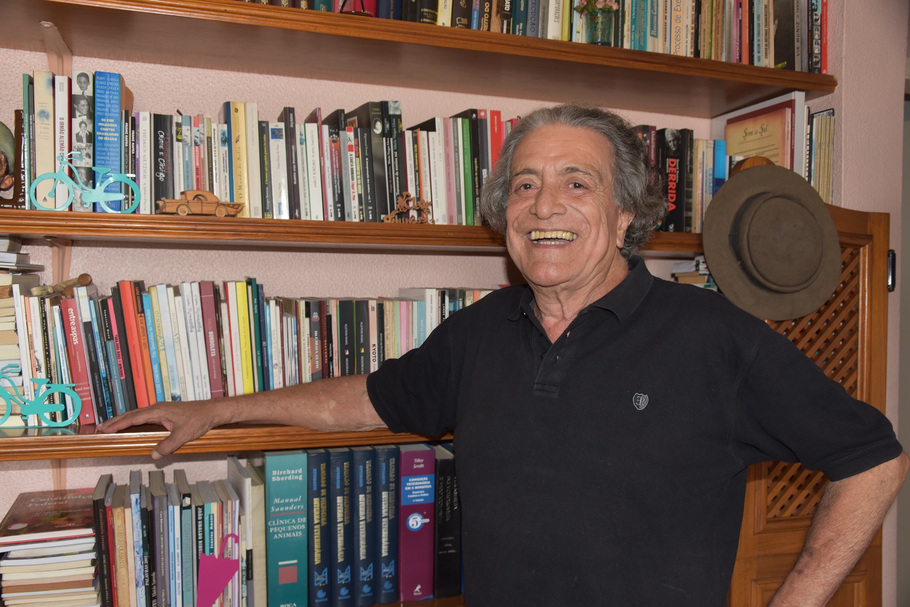 Foto de Jerônimo Jardim, sorrindo, em frente a uma estante de livros.