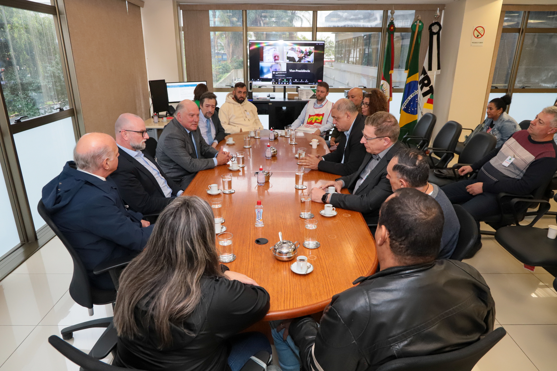 Foto da mesa de negociação. Aparecem desembargadores, trabalhadores e empresários.