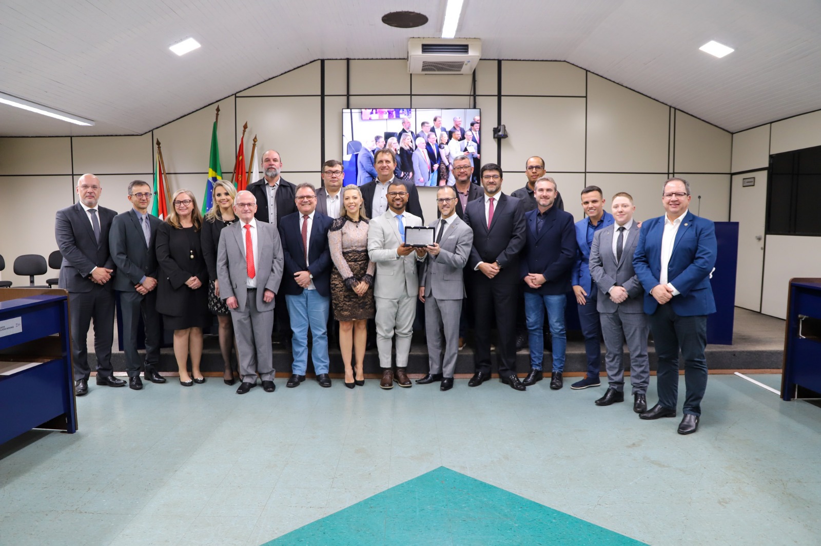 Foto das autoridades presentes na Câmara de Vereadores de Ijuí com a placa em homenagem à VT da cidade.