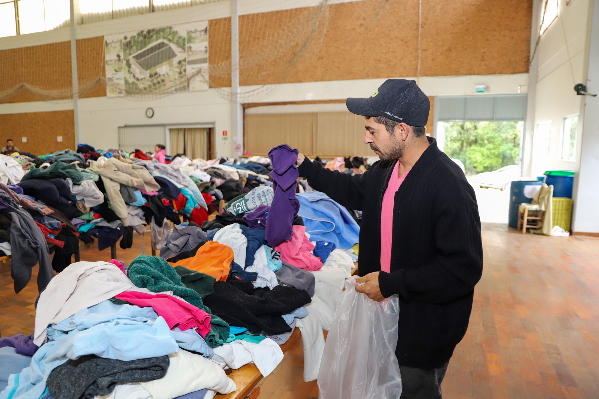 Foto do azulejista escolhendo roupas doadas.
