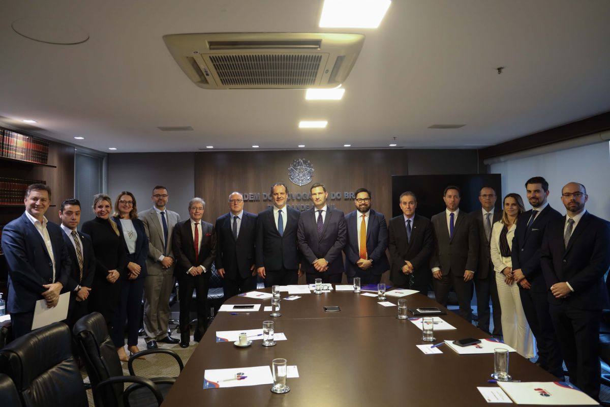 Foto dos representantes do grupo institucional na seda da OAB/RS. Os representantes estão em pé, em torno de uma mesa.