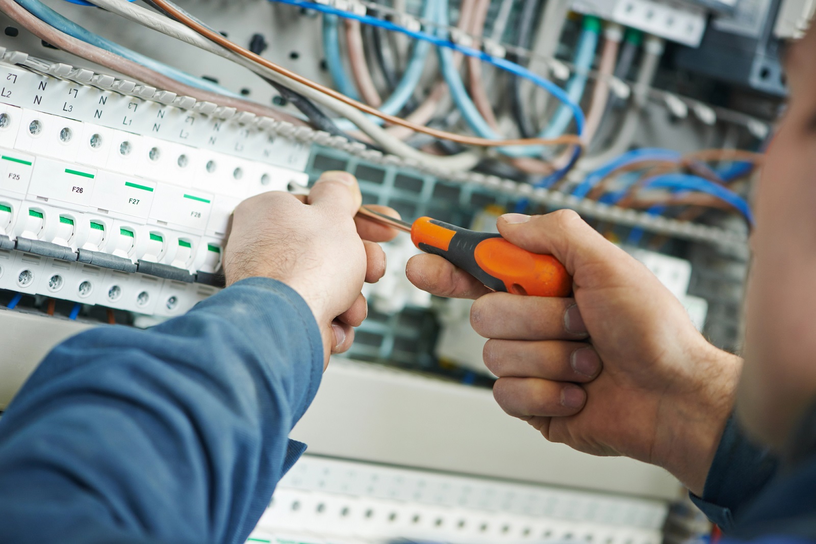 Foto de um eletricista consertando instalação elétrica com uma chave de fenda.