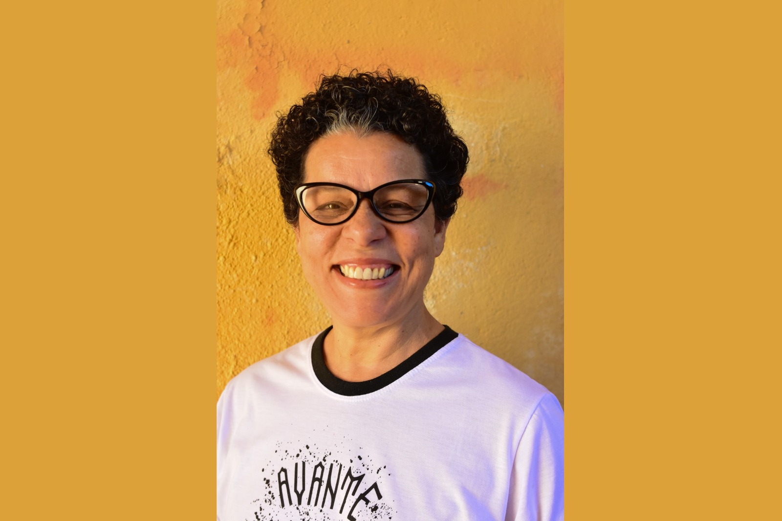 Dalva Maria Soares é  negra, de cabelo curto escuro. Usa óculos de armação preta e está sorrindo para a foto.