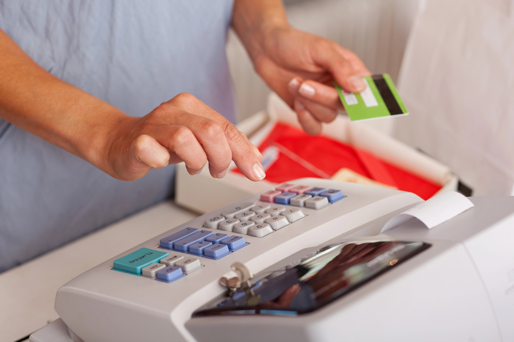 mãos femininas segurando cartão de crédito e operando caixa