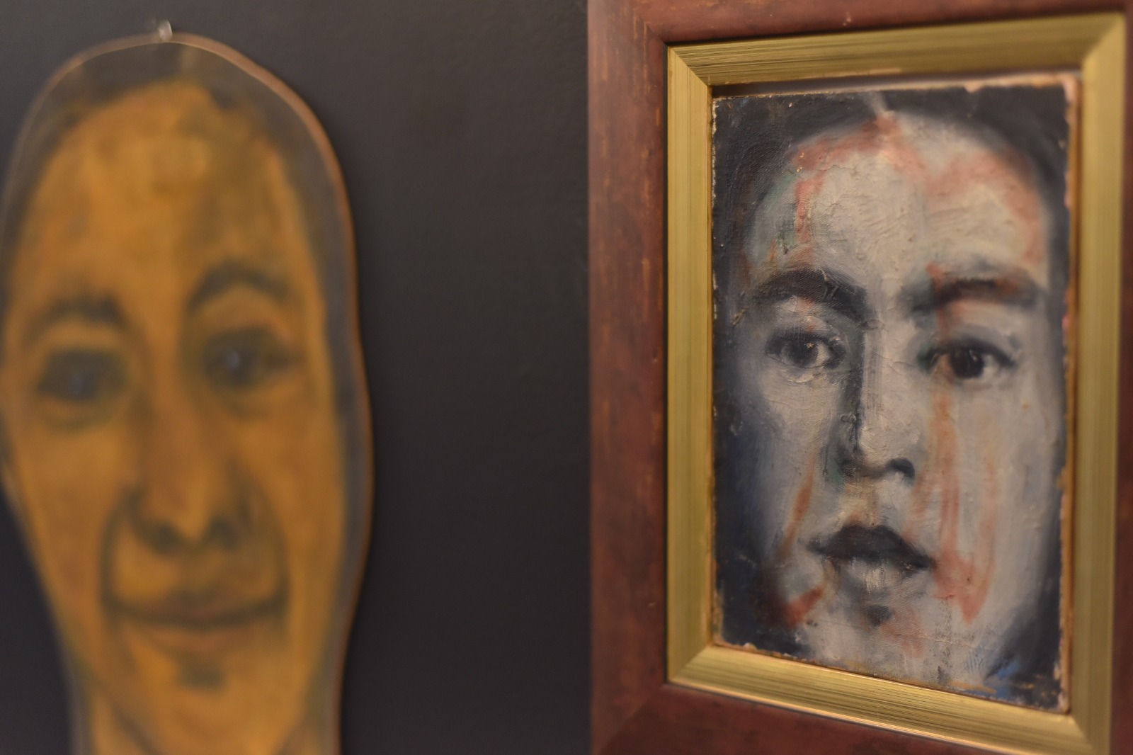 Foto de uma pintura de um rosto feminino em preto branco, mas com borrões vermelhos sobre a tela