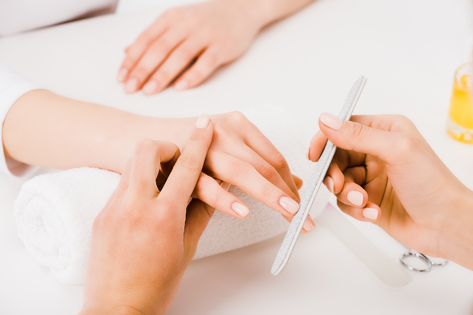 Foto de uma manicure fazendo as unhas de uma cliente.