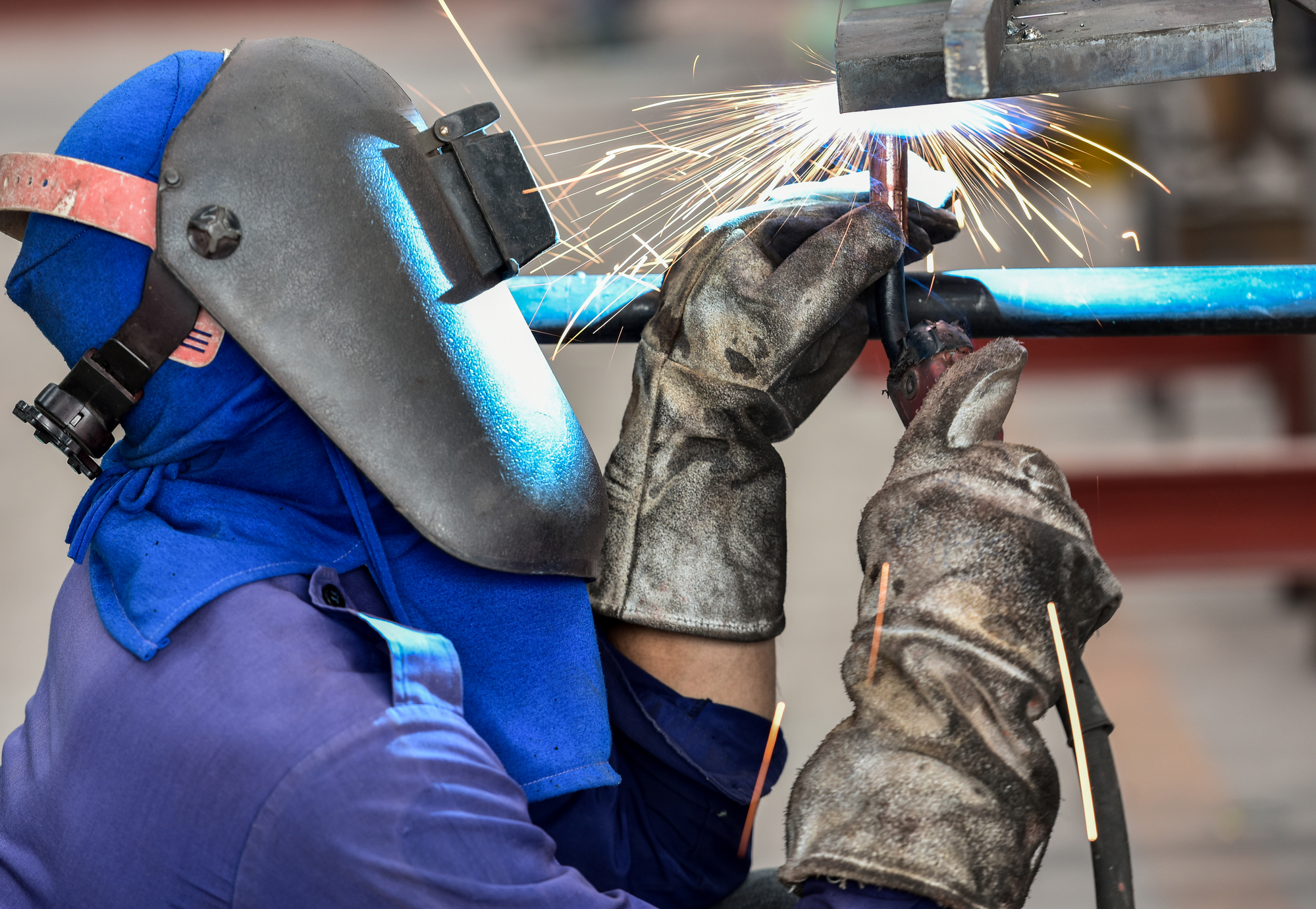 Foto ilustrativa de soldador trabalhando com máscara de proteção