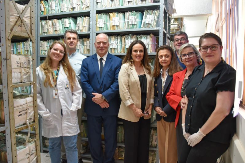 Grupo dos visitantes posando para foto entre as estantes com processos trabalhistas findos cedidos para guarda