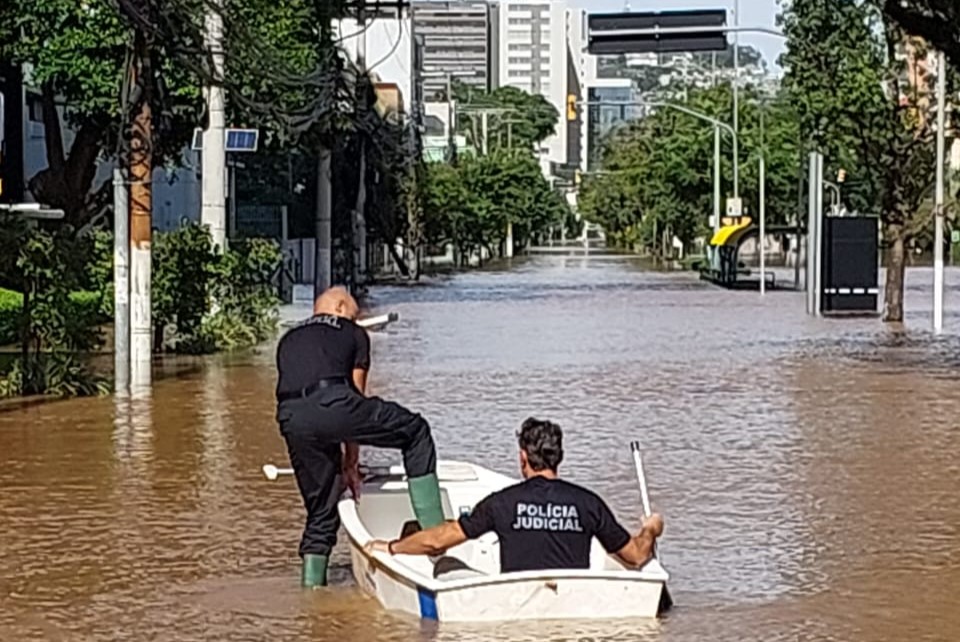 Equipe usa barco para percorrer áreas alagadas