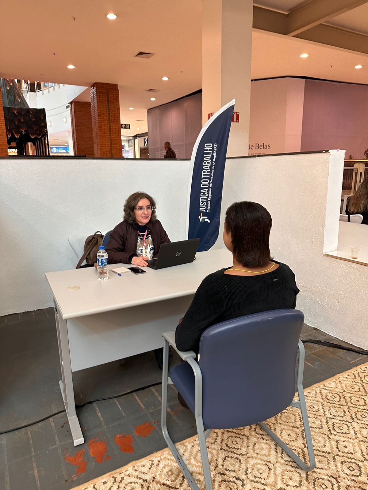 Servidora da CAP prestando atendimento a uma mulher no guichê
