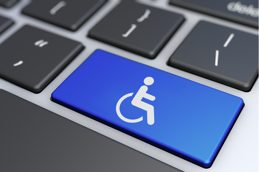 A imagem mostra um teclado de computador com uma tecla especial destacada. Essa tecla é azul e tem o símbolo internacional de acesso, que representa uma pessoa em uma cadeira de rodas. O ícone indica acessibilidade, sugerindo que o teclado ou o software associado é projetado para ser acessível a pessoas com deficiência. A tecla azul se destaca entre as outras teclas pretas e cinzas, enfatizando sua importância.