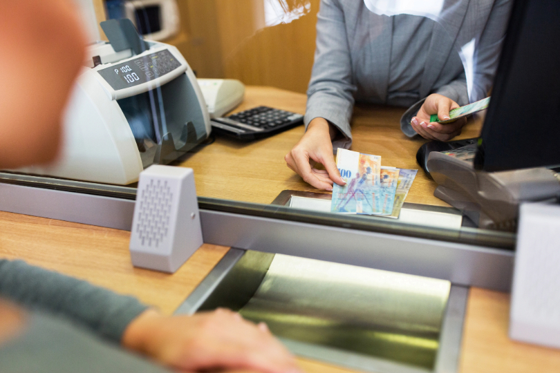 Caixa bancária alcança cédulas a cliente.