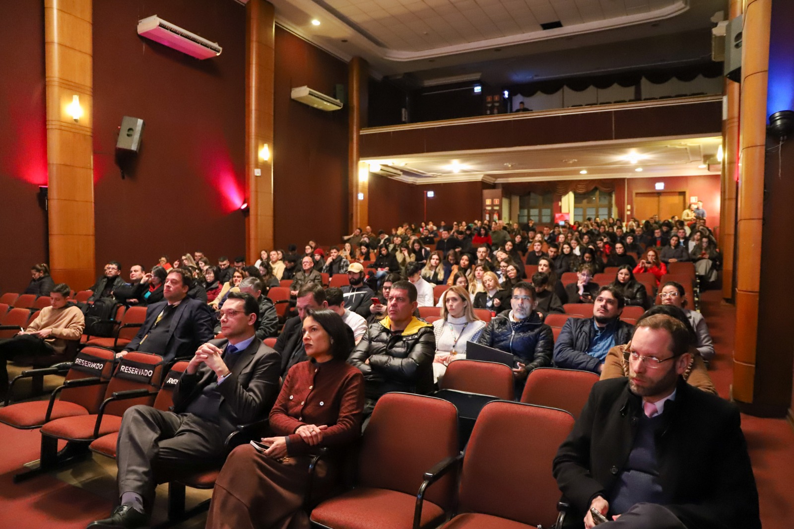 Imagem da plateia com auditório quase cheio.jfif