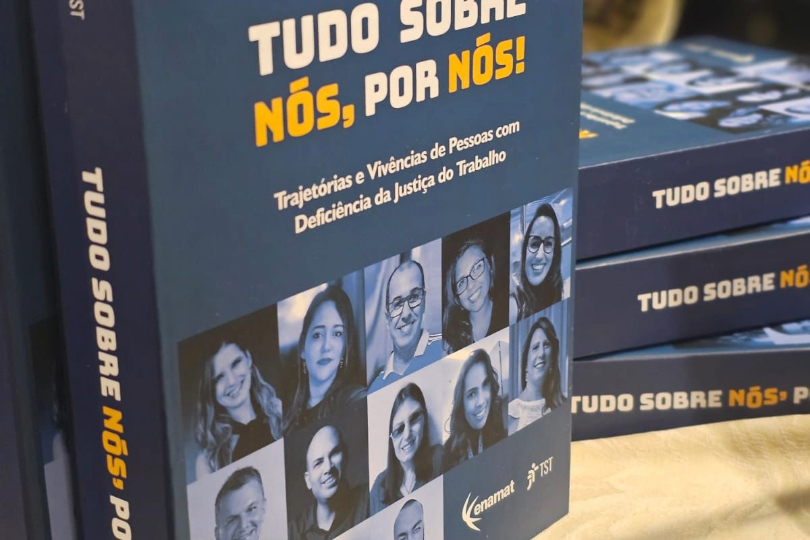Livro "Tudo sobre nós, por nós". Há um livro em pé e outros empilhados, sobre uma mesa.