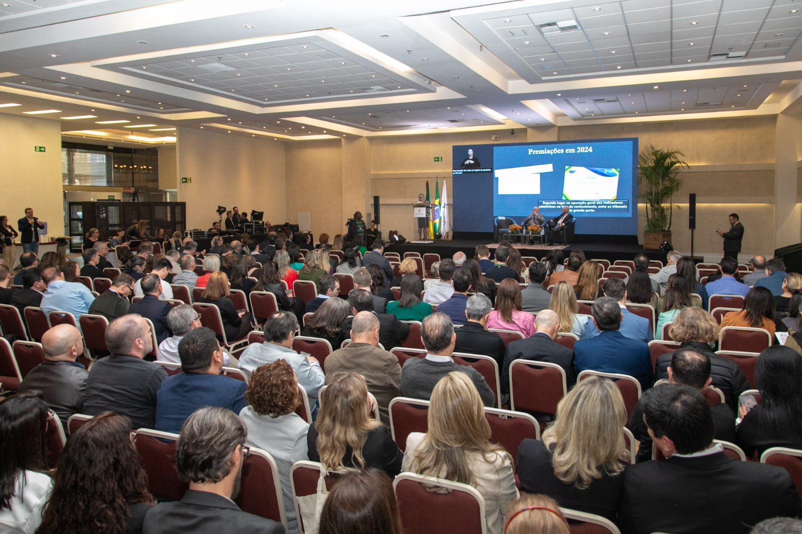 Foto em ângulo aberto do evento, mostrando público e palco