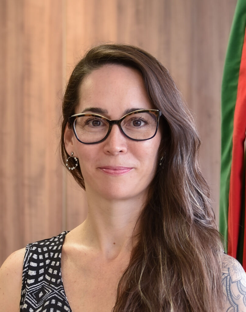 Fabiana tem o cabelo castanho para o lado, usa óculos de aro escuro e sorri. 