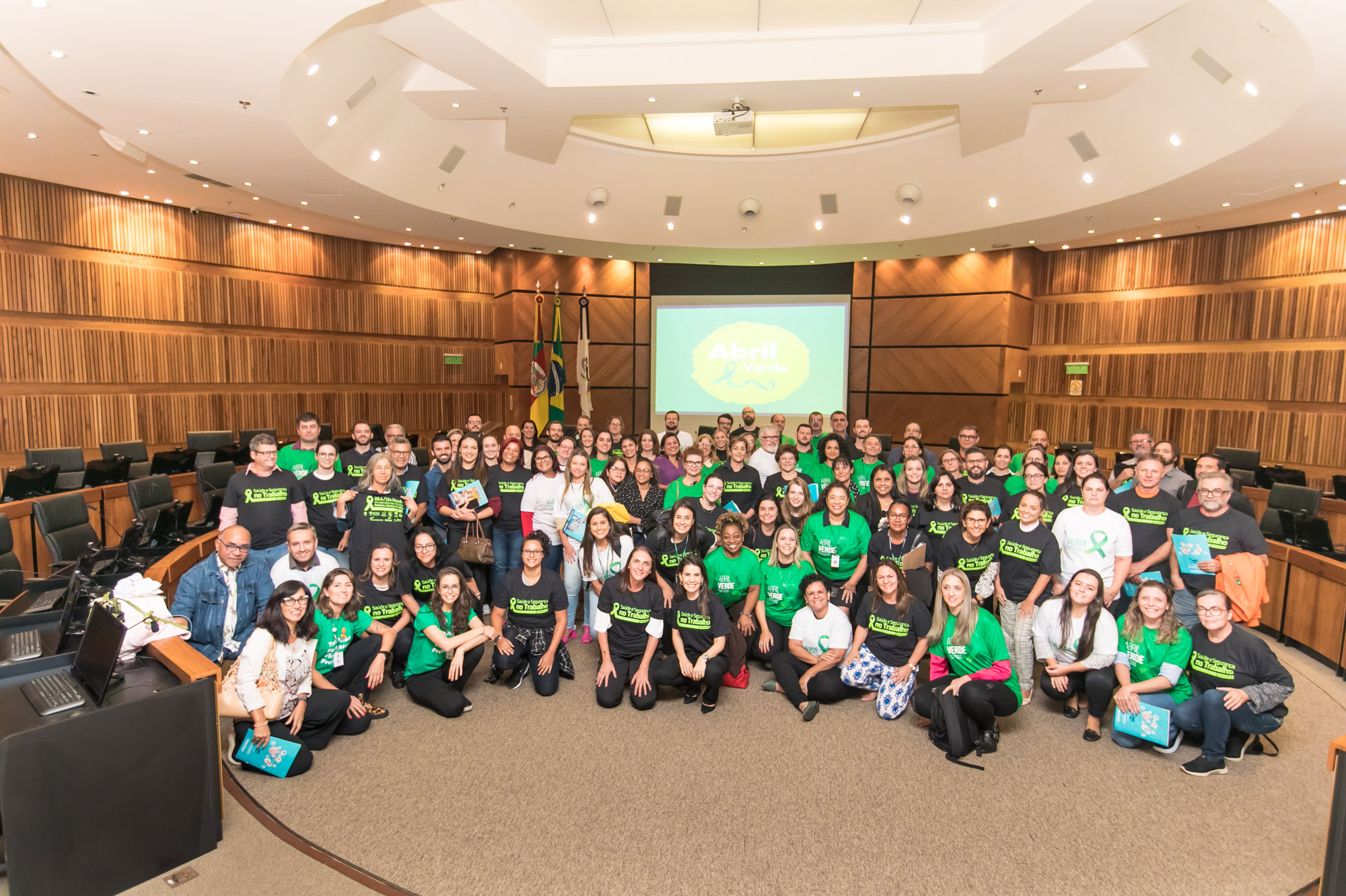 Participantes do evento posam para a foto na nave do plenário do TRT-4. São dezenas de pessoas, e muitas usam camisetas na cor verde, símbolo do Abril Verde. 