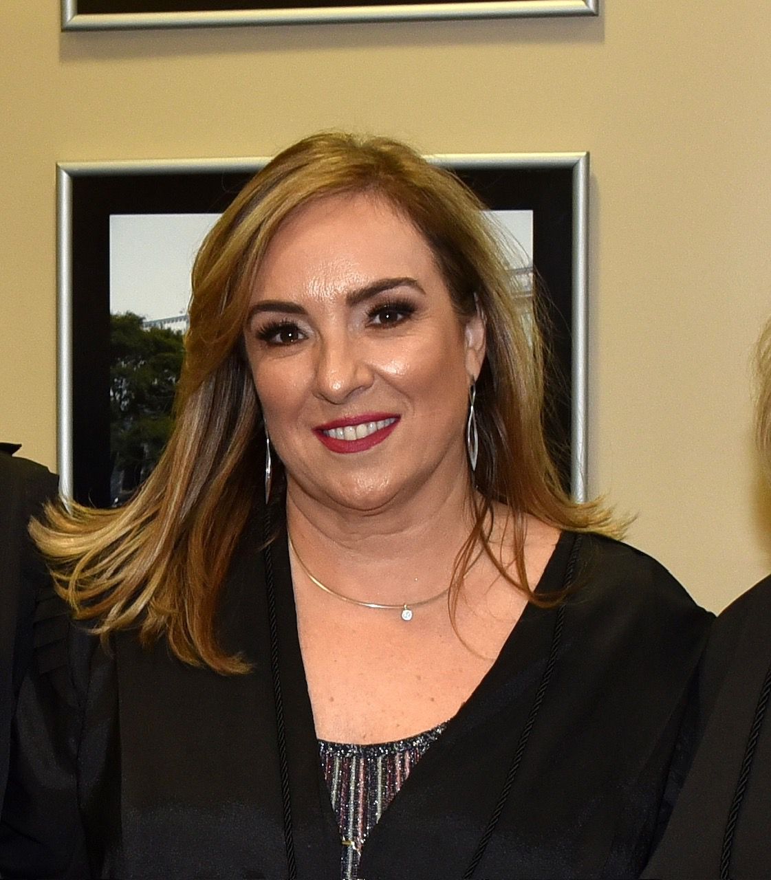 Mulher sorridente de cabelos loiros, batom avermelhado e pele branca
