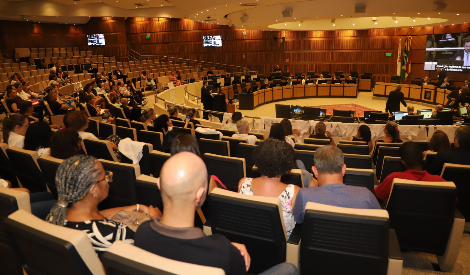 A imagem mostra o plenário do TRT em plano aberto. O público nas galerias e os desembargadores na nave do plenário.