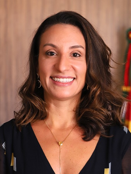 Mariana é branca, de cabelo liso escuro. Sorri para a foto. 