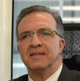 Foto de homem branco mais velho de terno com cabelo grisalho e óculos