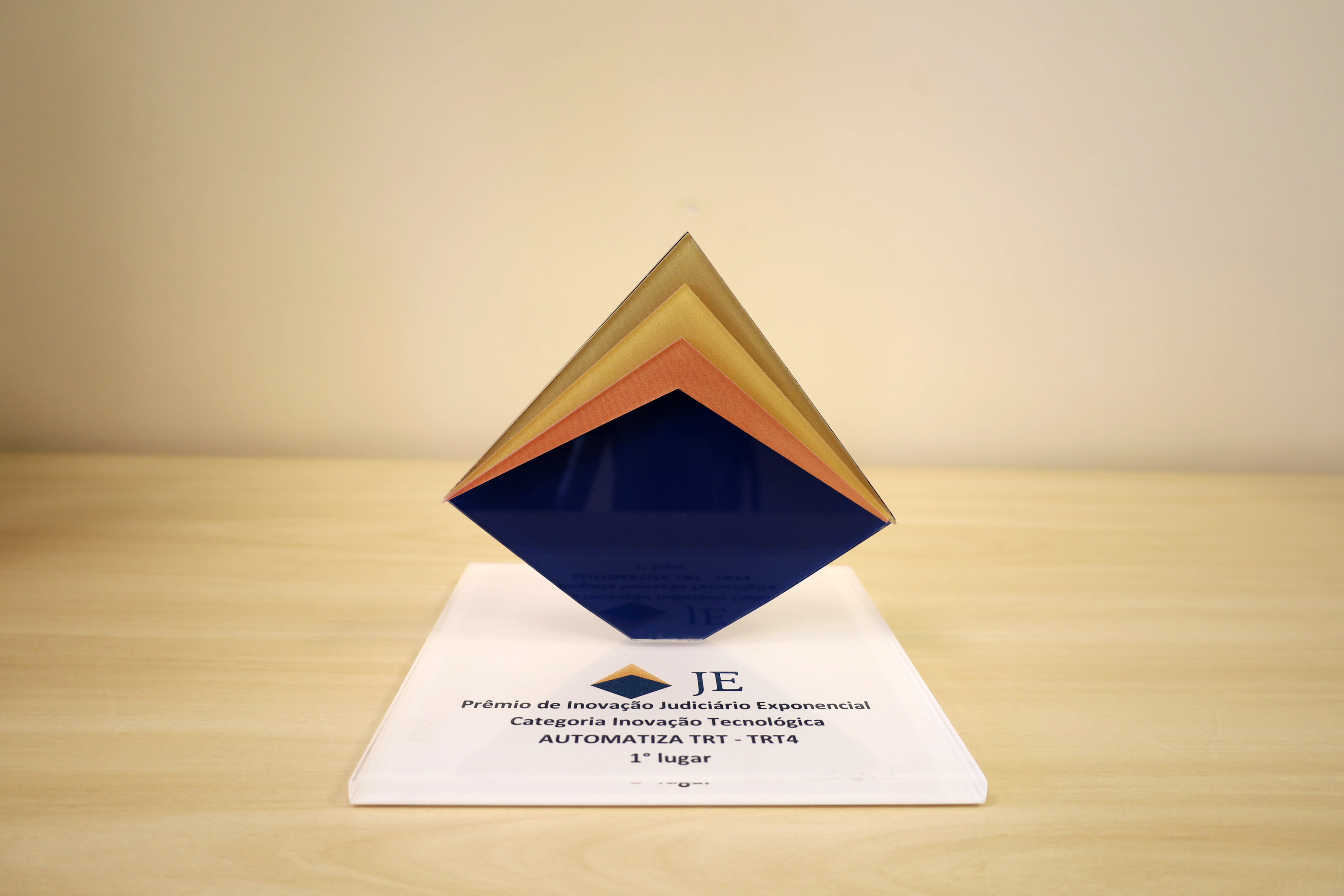 foto de troféu em formato de pirâmide triangular em sua maior parte azul escuro com detalhes no topo em tons de dourado numa base branca